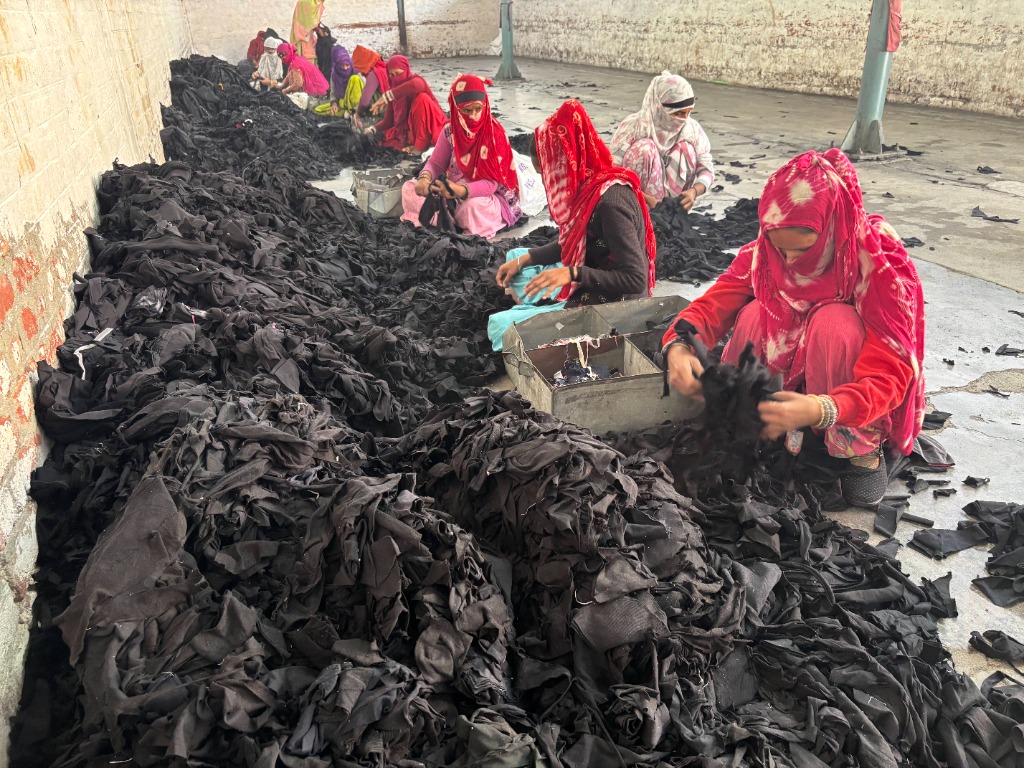 Textile workers sorting pre-consumer cotton fabric cutting scraps by color